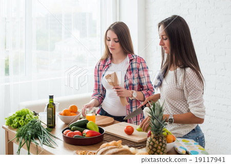 Gorgeous young Women preparing dinner in a kitchen Gorgeous young Women preparing dinner in a kitchen 19117941