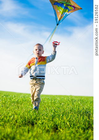 Young boy playing with his kite in a green field. 19126582