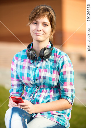 Smiling young college girl texting on a cell phone. Campus Smiling young college girl texting on a cell phone. Campus 19126686
