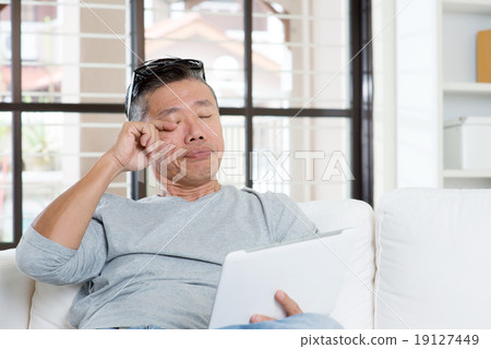 Stock Photo: Mature Asian man eyes pain while using tablet computer