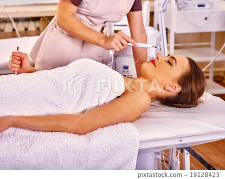 Man receiving electric facial massage. 19128423