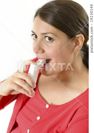 Woman using medicinal throat spray Woman using medicinal throat spray 19130149