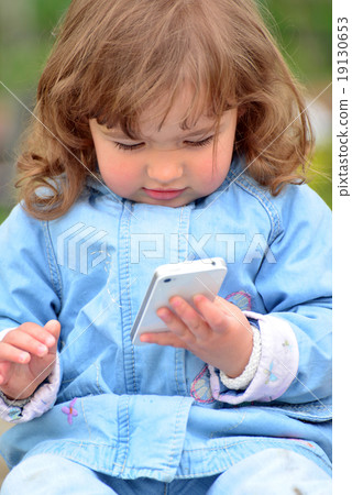 Girl two years, with a cell phone in the park Girl two years, with a cell phone in the park 19130653