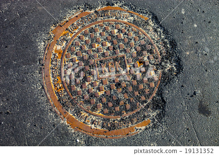 Manhole with rusty metal cover in asphalt surface 19131352
