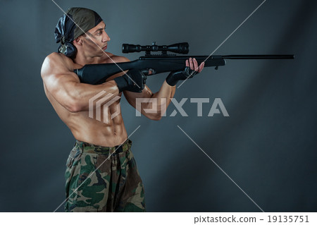 Man shoots from a rifle. 19135751