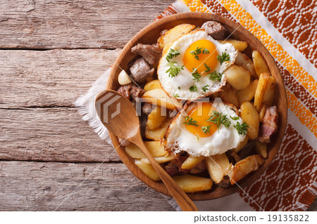 fried potatoes with meat and eggs in a bowl 19135822