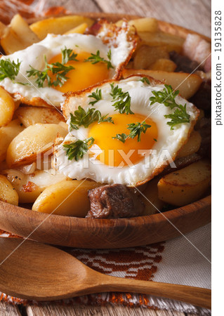 fried potatoes with meat, bacon and eggs closeup 19135828