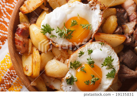 fried potatoes with meat, bacon and eggs close-up 19135831