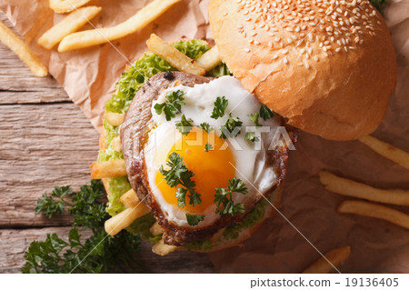 sandwich with meat, a fried egg and fries close-up 19136405