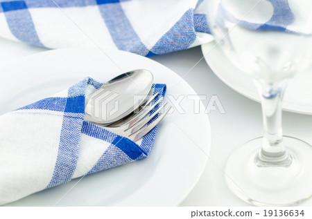 Spoon and fork at blue napkin on white plate 19136634