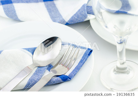 Spoon and fork at blue napkin on white plate 19136635