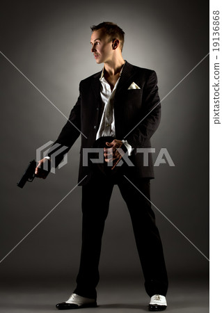 Handsome man dressed as gangster holding gun Handsome man dressed as gangster holding gun 19136868