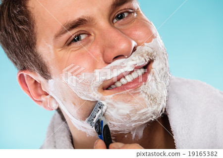 Man shaving using razor with cream foam. 19165382