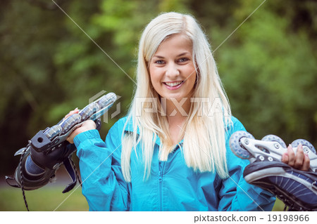 Happy blonde holding inline skates Happy blonde holding inline skates 19198966