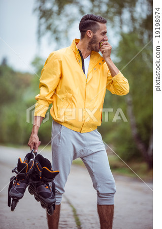 Handsome man holding inline skates Handsome man holding inline skates 19198974