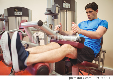 Fit man using weights machine for legs 19199024