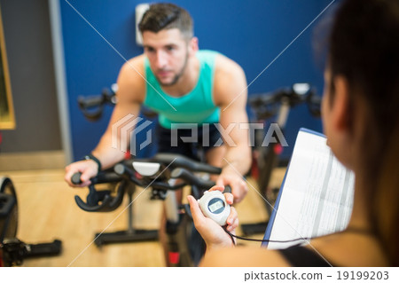 Trainer timing man on exercise bike Trainer timing man on exercise bike 19199203