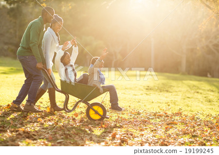 Young parents holding their children in a wheelbarrow 19199245