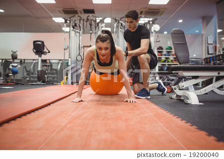 Fit woman working out with trainer 19200040
