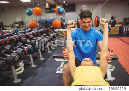 Woman lifting dumbbells with her trainer 19200229