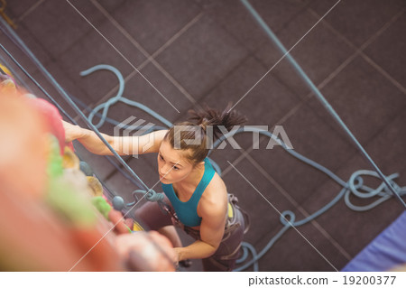 Woman climbing up rock wall 19200377
