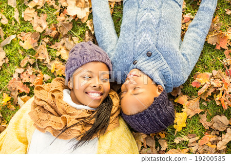 Young mother with her daughter lying in leaves Young mother with her daughter lying in leaves 19200585