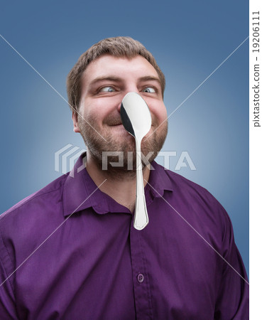 Adult man holds a spoon on his nose 19206111