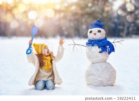 girl playing with a snowman girl playing with a snowman 19222411