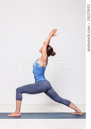 Sporty woman practices yoga Warrior pose asana  19225915