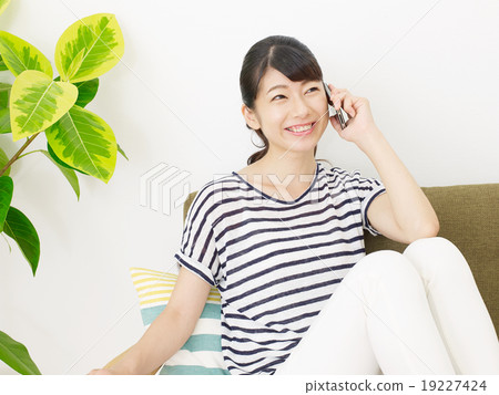 一個女人誰在一個房間裡用智能手機說話 19227424