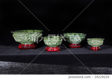 Four Jade bowls with wooden base isolated on dark 19229220