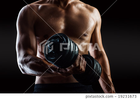 Bodybuilder with beads of sweat training in gym.  19231673
