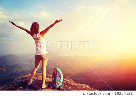 cheering woman hiker open arms at mountain peak 19234121