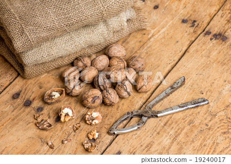 walnuts and nutcracker on an old rustic table 19240017