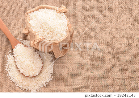 White paddy rice on wooden spoon and the hemp sack White paddy rice on wooden spoon and the hemp sack 19242143