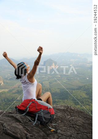 cheering woman hiker open arms at mountain peak 19244512