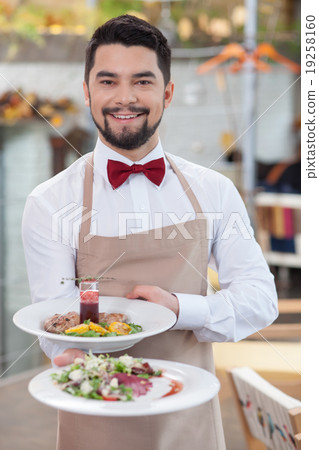 Handsome young waiter is working in restaurant Handsome young waiter is working in restaurant 19258160