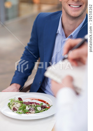 Skillful male cafe worker is serving a client Skillful male cafe worker is serving a client 19258162
