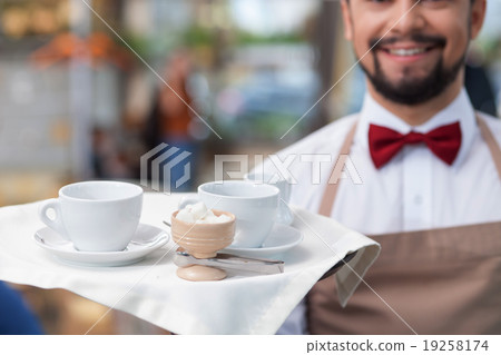 Handsome male cafe worker is serving a client Handsome male cafe worker is serving a client 19258174
