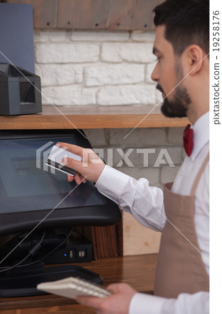 Attractive male cafe worker is receiving payment Attractive male cafe worker is receiving payment 19258176