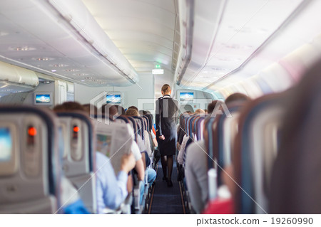 Stewardess and passengers on commercial airplane. 19260990