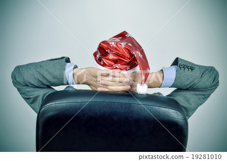 businessman with santa hat relaxing in his office businessman with santa hat relaxing in his office 19281010