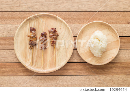 Grilled pork with bamboo stick and Thai sticky rice on wooden di 19294654