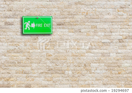 Green fire exit sign on stone wall 19294697