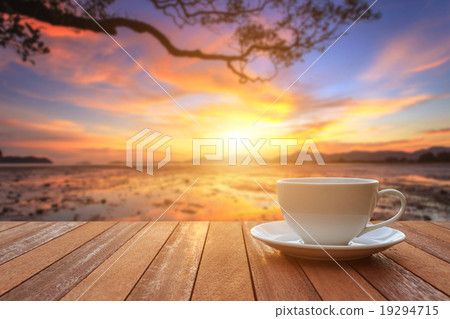 White coffee cup on wood table and view of sunset or sunrise bac White coffee cup on wood table and view of sunset or sunrise bac 19294715