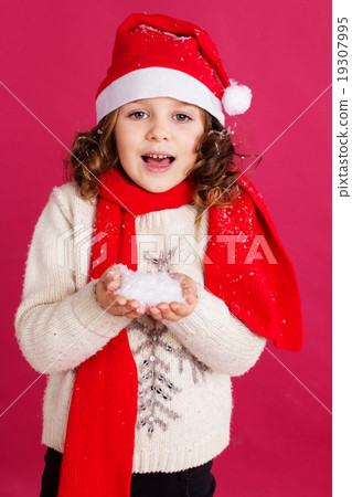 Little girl in santa hat is holding fake snow  19307995