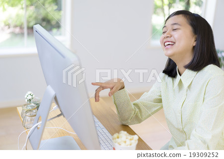 A girl with a smile watching a computer 19309252