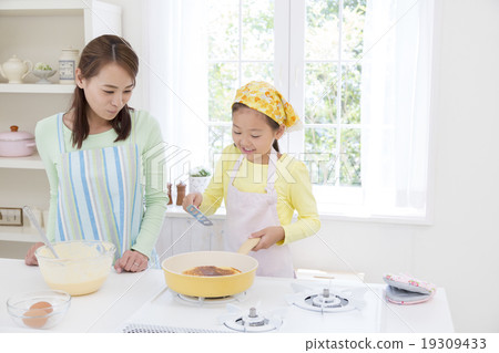 Mother and daughter standing in the kitchen 19309433