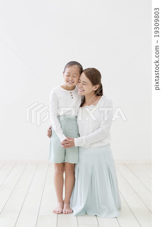 Mother and daughter bringing cheeks together 19309803