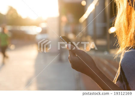 closeup women using smartphone at sunset 19312169